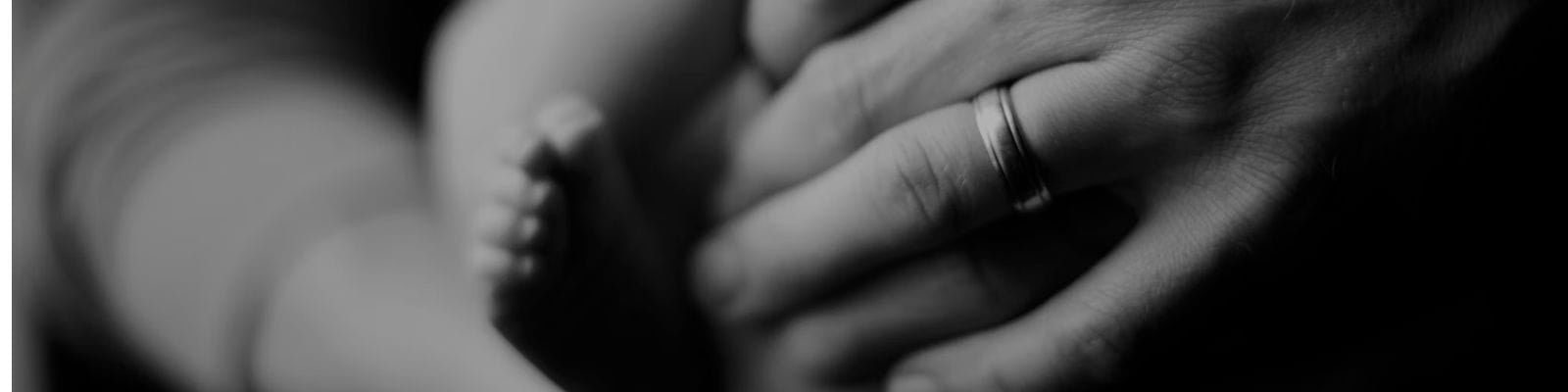 Parent or caregiver gently holding a newborn baby’s foot.