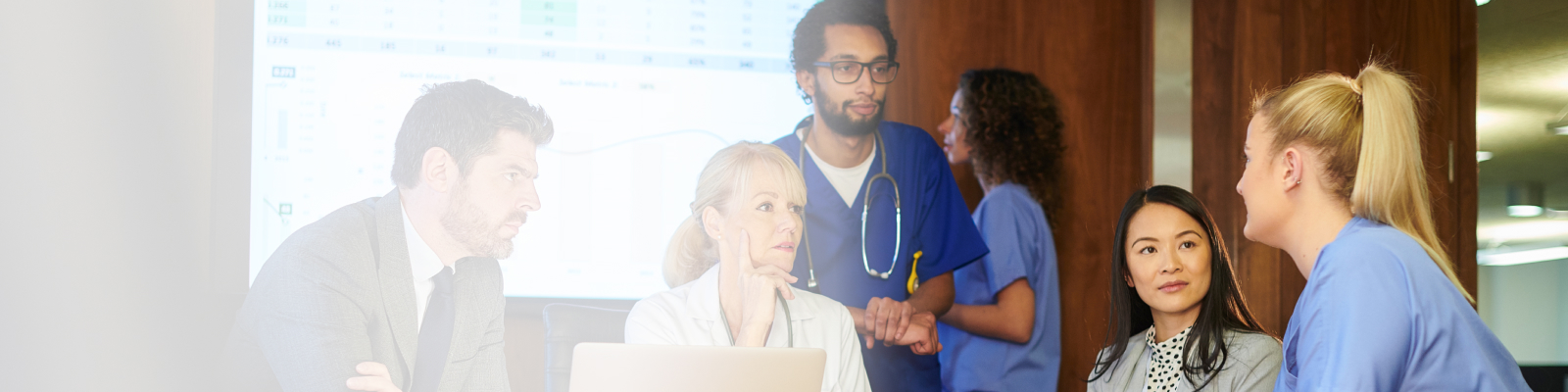 A group of clinicians and business professionals collaborating in a meeting room.